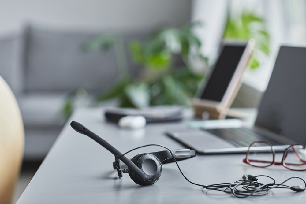 A headset on a desk beside a laptop